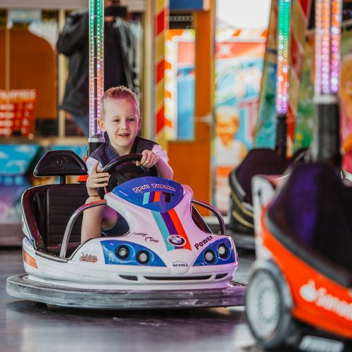Ein Kind sitzt strahlend in einem Autoscooter und fährt.