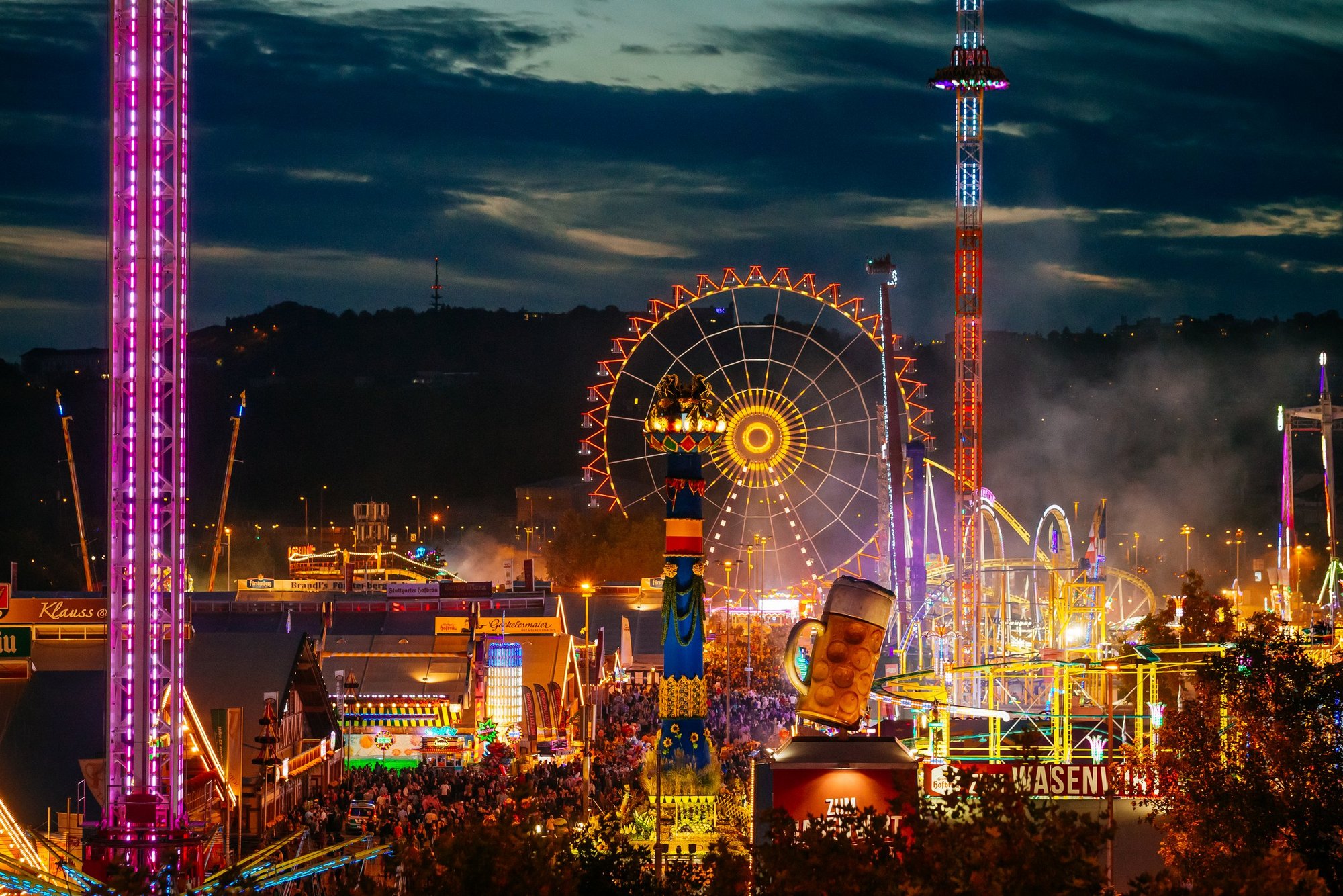 Vogelperspektive auf das Volksfest bei Dunkelheit mit unzähligen Lichtern, beleuchteten Fahrgeschäften und den Festzelten