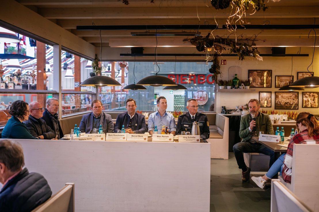 Eröffnungspressekonferenz im Festzelt "Beim Benz". Die Sprecher sitzen gemeinsam an einem Tisch. Von links nach rechts: Stefanie Hirrle - Unternehmensspercherin der in.Stuttgart Veranstaltungsgesellschaft, Wulf Wager vom Volksfestverein, Andreas Kroll - Geschäftsführer der in.Stuttgart, Mark Roschmann - Sprecher der Schausteller, Werner Klauss - Sprecher der Festwirte, Marc Reinelt - Vertreter der Wasenboje, Jörg Schiebe - Leiter des Polizeireviers Bad Cannstatt und Marcus Christen - Abteilungsleiter der in.Stuttgart