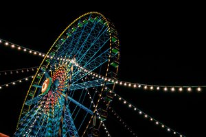 Blick von unten bei Nacht auf das bunt beleuchtete Riesenrad.