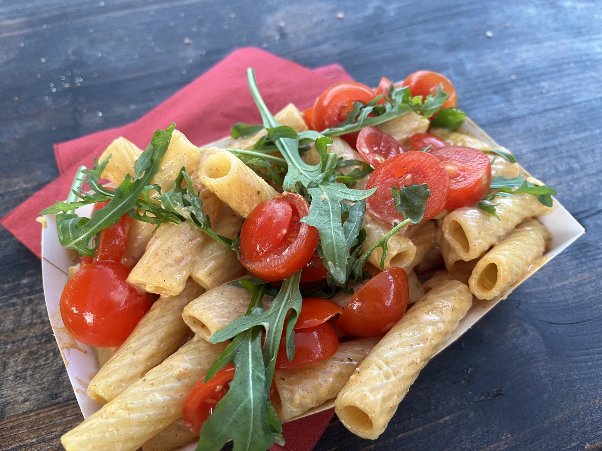 Eine Portion Pasta mit Rucola und Tomaten, die in einem Käselaib gewendet wurden.