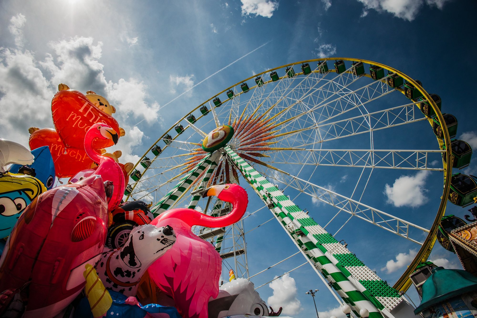 Das Riesenrad Bellevue von unten betrachtet. Daneben schweben Luftballons in der Luft.
