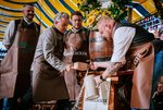 Der Oberbürgermeister schläft das Fass an. Bier fließt in einen Krug. Braumeister hält den Krug und den Zapfhahn..