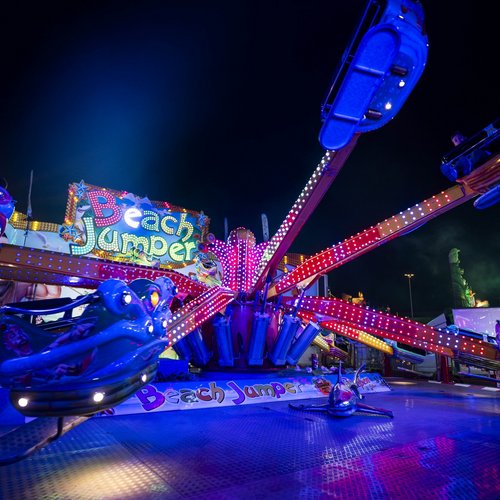 Das Fahrgeschäft "Beach Jumper" bei Dunkelheit in blaues Licht getaucht