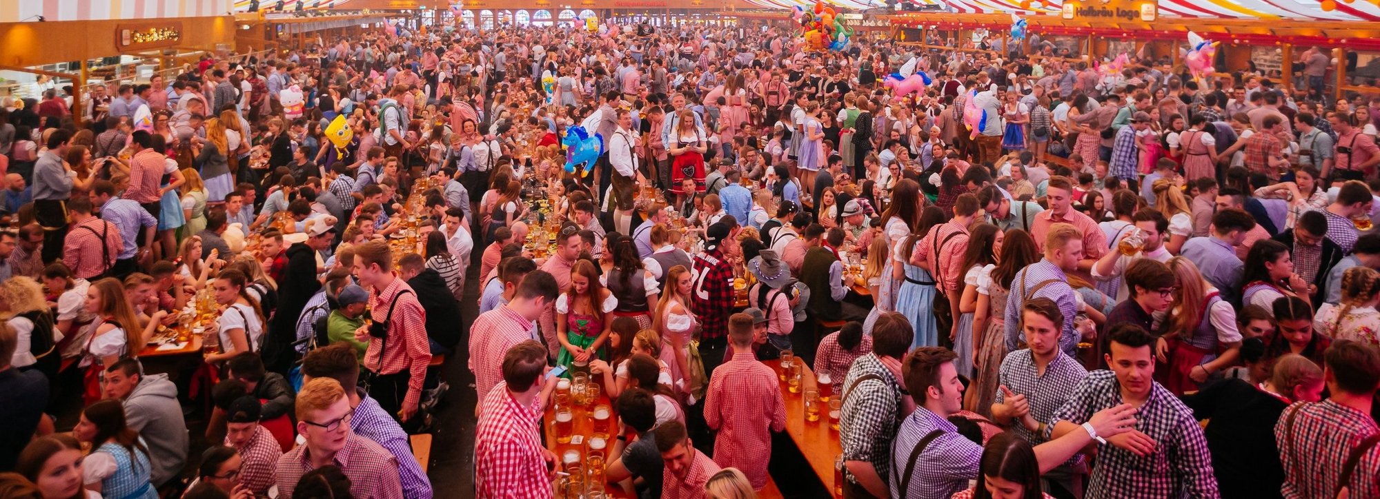 Unzählige Menschen stehen in einem der Festzelte auf den Bänken und feiern. 