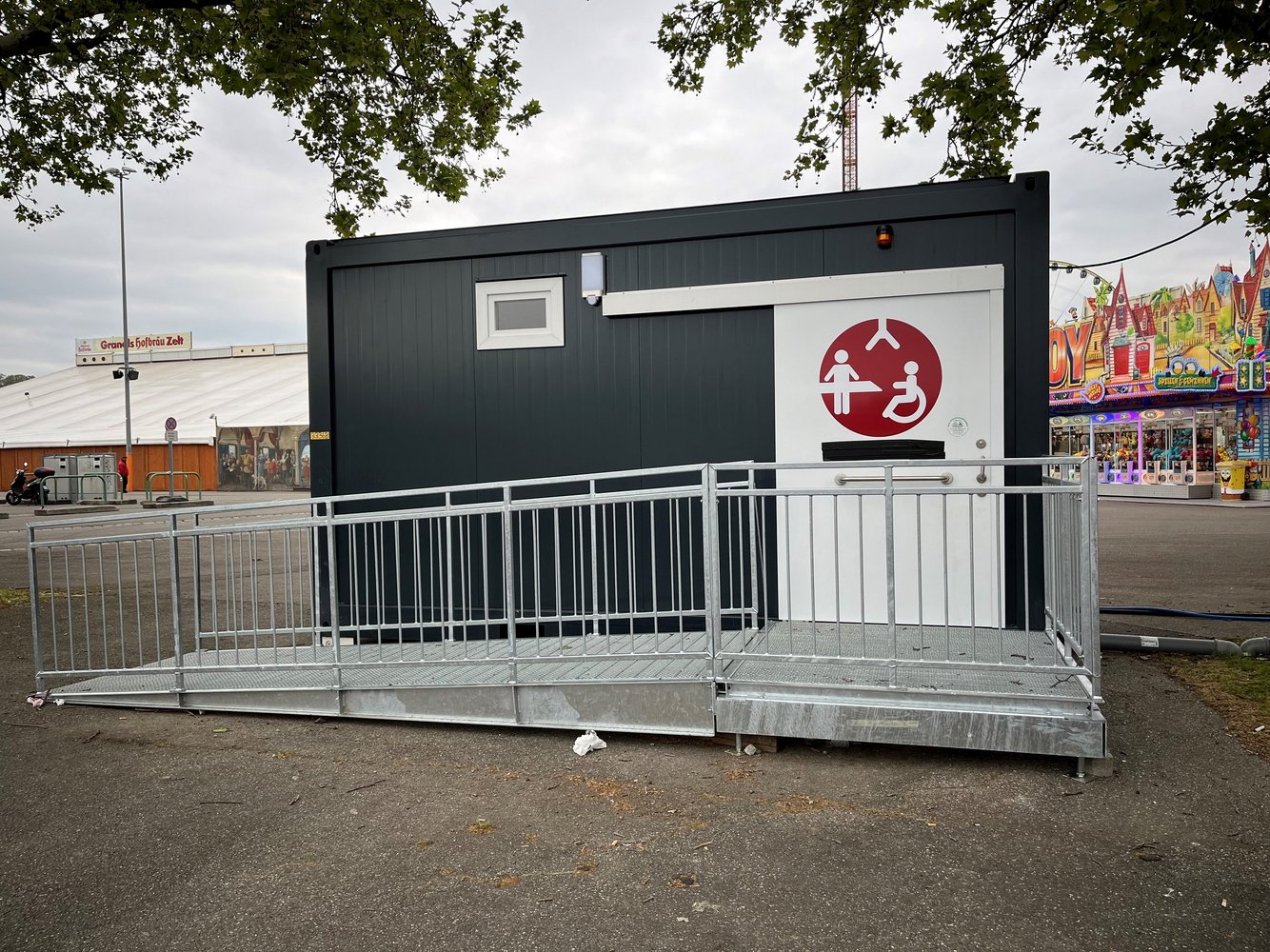 Ein grauer Container mit weißer Tür, auf der das Logo der Toilette für alle klebt.