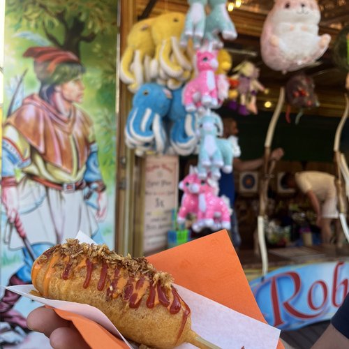 Vegane Corn Dogs - ein Würstchen in einem Teig-Mantel, das an einem Stil gereicht wird und noch mit soße verziert wird.